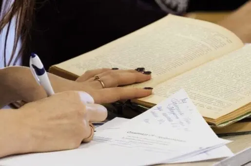 student taking exam, writing on paper