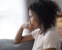 young african american woman looking out a window in distress
