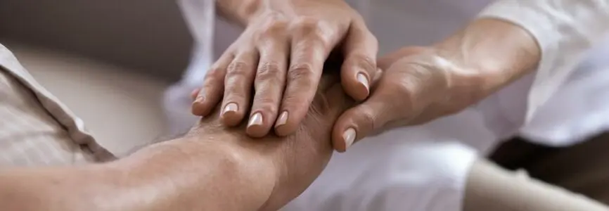 Close up of professional female caregiver hold senior male patient hands showing support and empathy at nursing home, caring doctor or nurse comfort support mature man, elderly healthcare concept