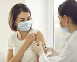 Young patient in a medical face mask getting an antiviral vaccine at the hospital