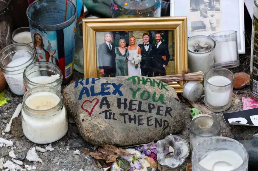 3DN0JCG A rock with painted text, flowers, candles, and family pictures are arranged on the street at the Alex Pretti memorial site in Minneapolis.