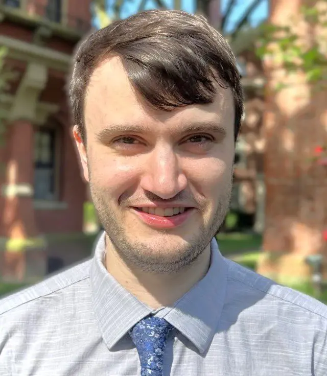 Ian headshot white young man with brown hair smiling.