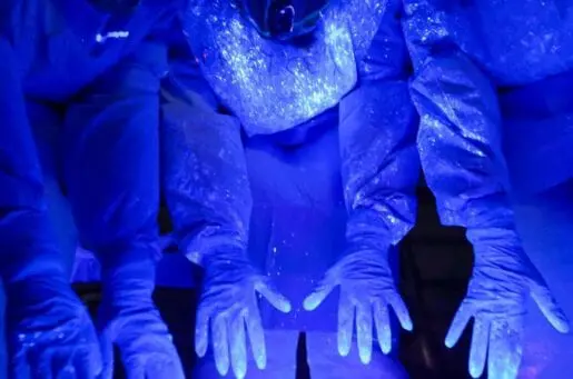 blue hands and body glowing under blacklight, showing the germs on their hands and bodies