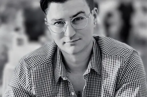 young white man with black hair and round glasses
