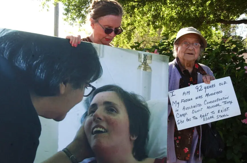 woman holding a photo of white woman in hospital bed