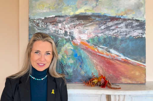 white woman with blond hair standing in front of colorful abstract painting