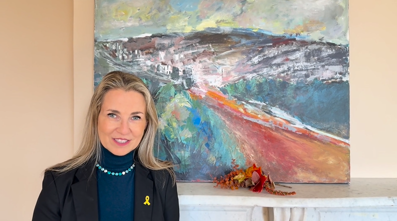 white woman with blond hair standing in front of colorful abstract painting