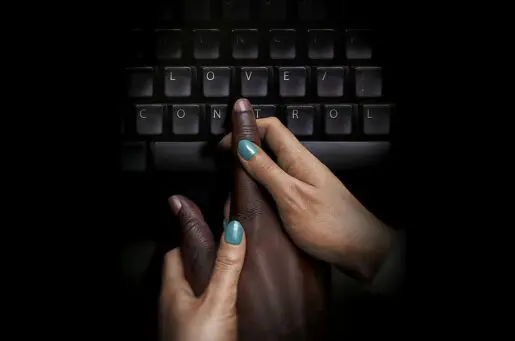 white hand guiding black hand to type on keyboard