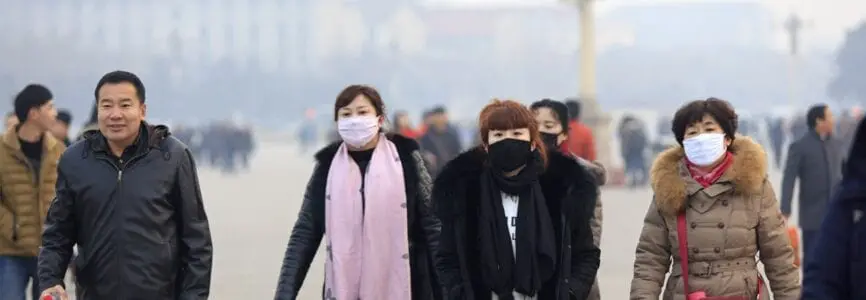 two people in masks and heavy winter coats walking through busy streets