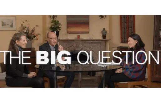 A blond white woman, an Asian man, and a black haired woman laugh at a table