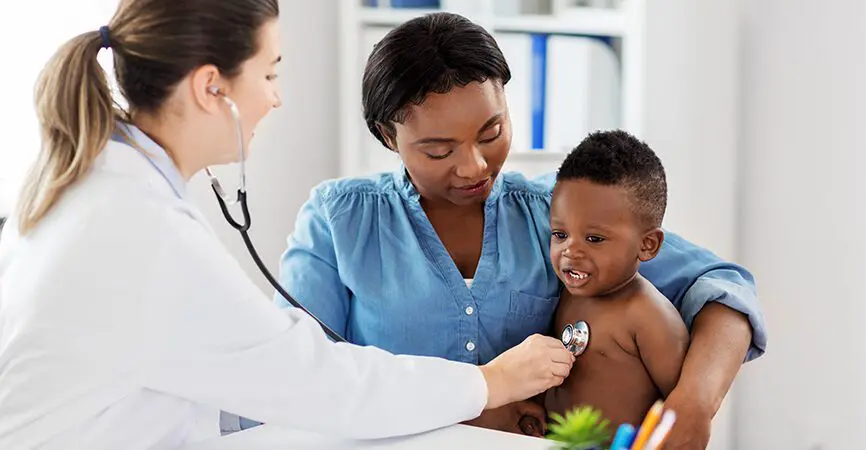medicine, healthcare and pediatry concept - doctor with stethoscope listening to african american baby boy on medical exam at clinic