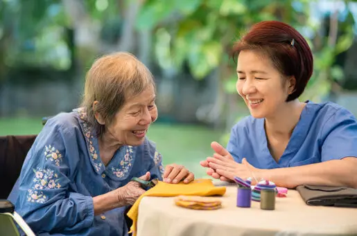 older asian woman cutting fabric with young nurse