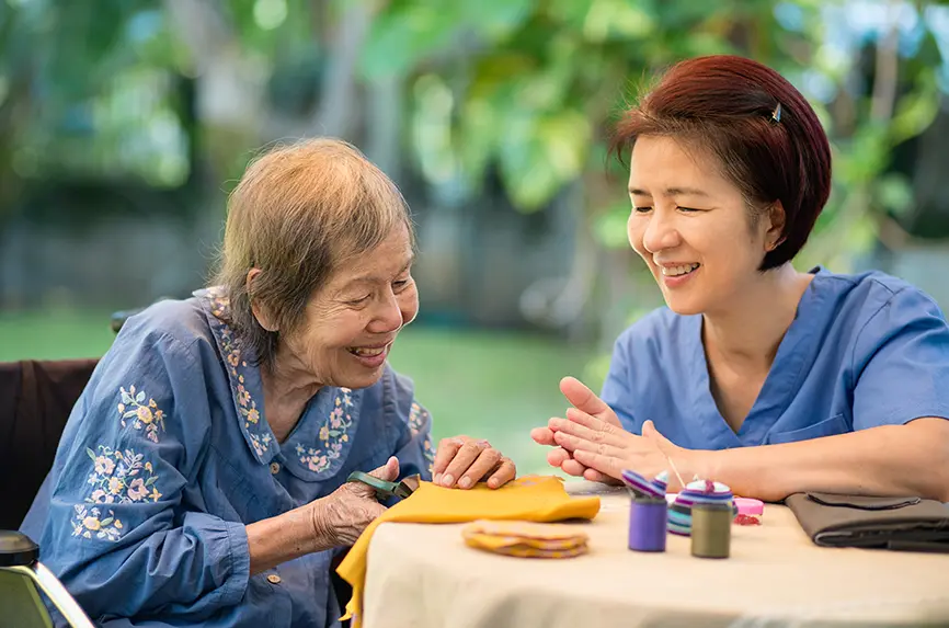 older asian woman cutting fabric with young nurse