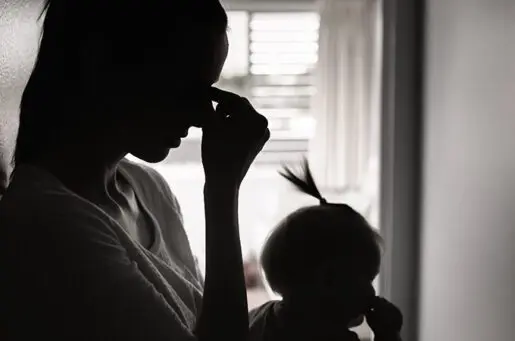 silhouette of a woman with her head in her hands and a baby in her lap