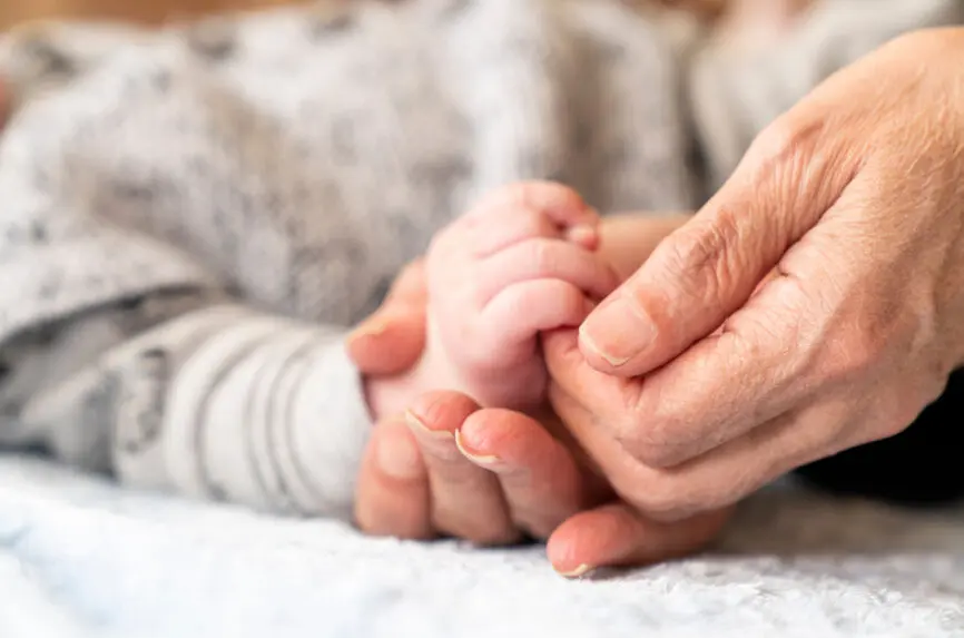 A baby's hand is being held by a parent. The concept of family love and protection