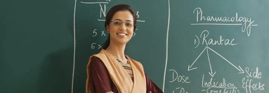 smiling woman standing in front of a chalkboard