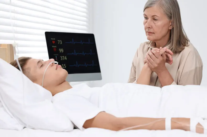 Coma patient. Sad mature woman near her unconscious son in hospital