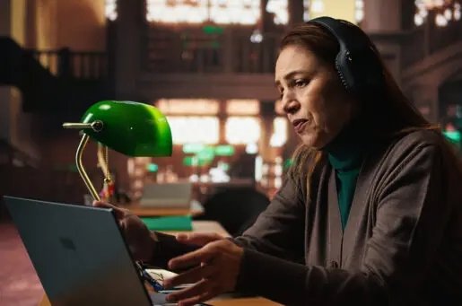 white Female student participates in online class via laptop in a campus library,