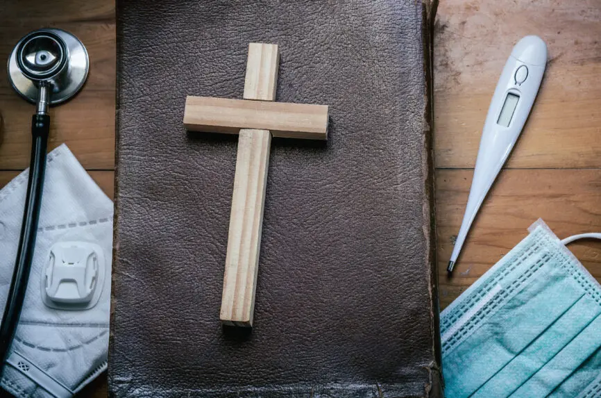 Cross with Holy Bible on wooden table, belief in treatment of God, Christian treatment concept.