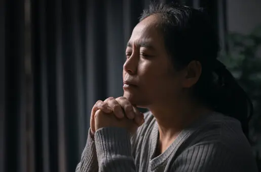 young hispanic woman with eyes closed, hands in prayer