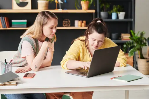 two white women, one with downs on computer