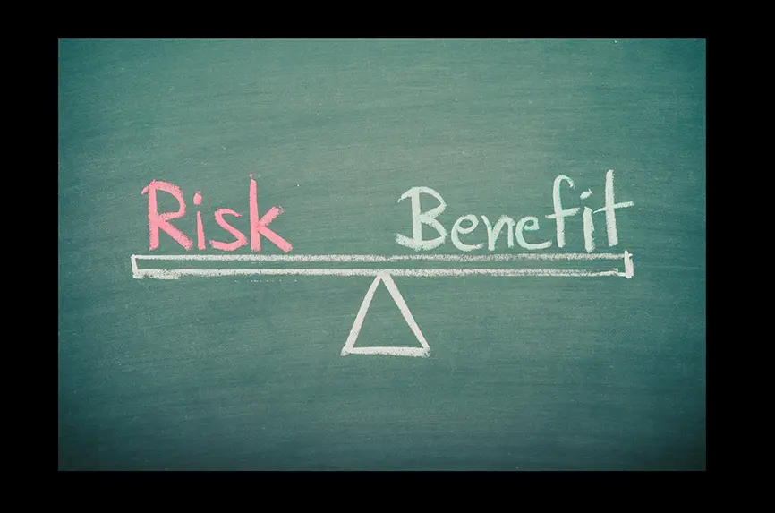 chalkboard with words risk and benefit written on a scale
