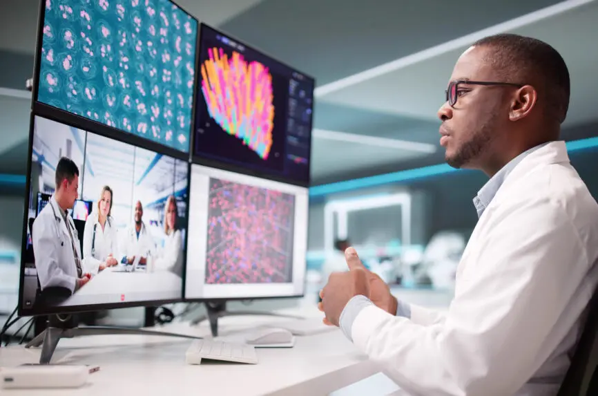 man in white coat talking to others on screen