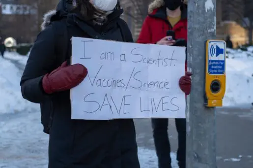 person holding sign that says I am a scientist, vaccines/science saves lives
