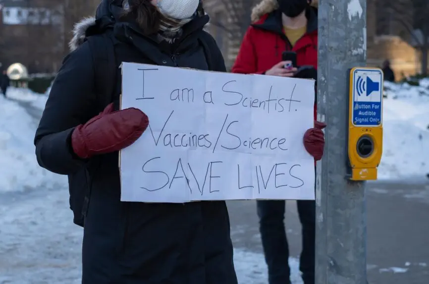 person holding sign that says I am a scientist, vaccines/science saves lives