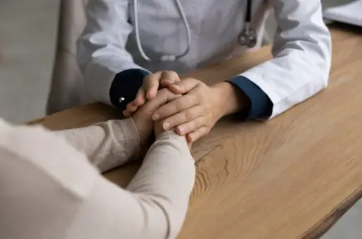 doctor and patient holding hands on a desk
