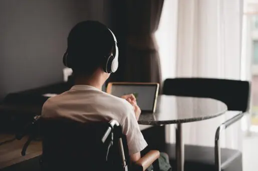 disabled boy with headphones sitting and looking at screen