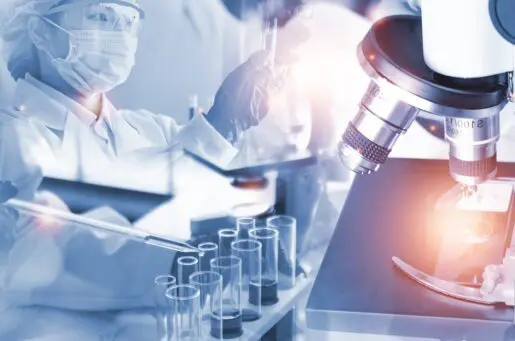 scientist experimenting and analyzing gene therapy data in lab with lab coat, mask, hat, gloves and goggles.