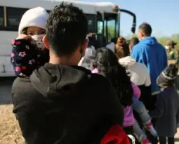 the back of a man walking toward a bus holding a child