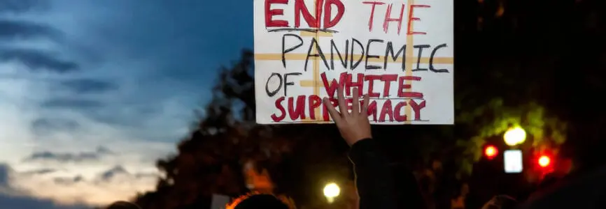 man of color holding a white sign stating 