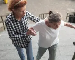 younger white woman helping older white woman to walk