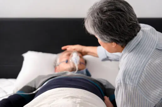 back of woman's head leaning over hospital beside