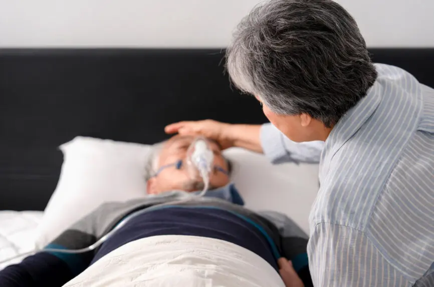 back of woman's head leaning over hospital beside