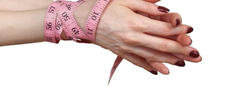 Female hands tied with tape measure fighting eating disorder