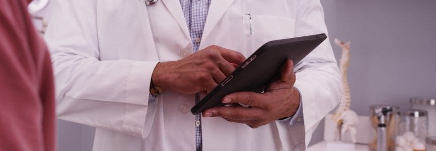 Portrait of male black doctor using tablet device with an elderly patient.