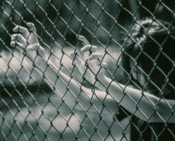 woman grabbing onto a chainlink fence