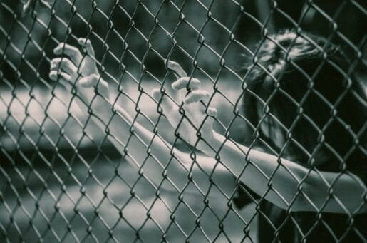 woman grabbing onto a chainlink fence