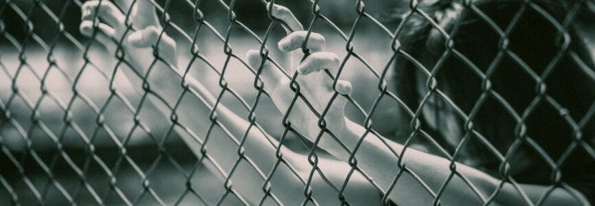 woman grabbing onto a chainlink fence