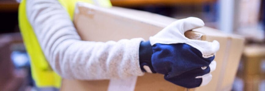 Unrecognizable female warehouse worker loading up a pallet truck with boxes.