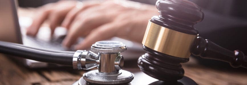 Close-up Of Stethoscope And Gavel On Wooden Desk