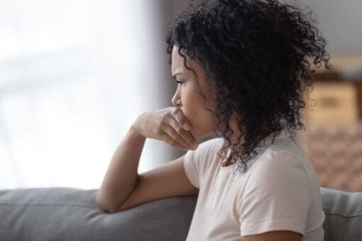 young african american woman looking out a window in distress