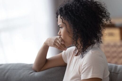 young african american woman looking out a window in distress