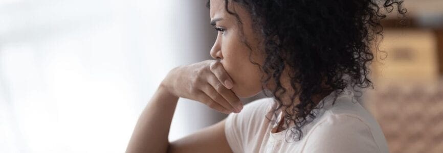 young african american woman looking out a window in distress