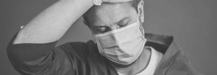 COVID-19. Exhausted Doctor looking worried as the coronavirus infected cases and death tolls rises. Emotional stressed of health workers needing support, Personal Protective gear and medical supplies.