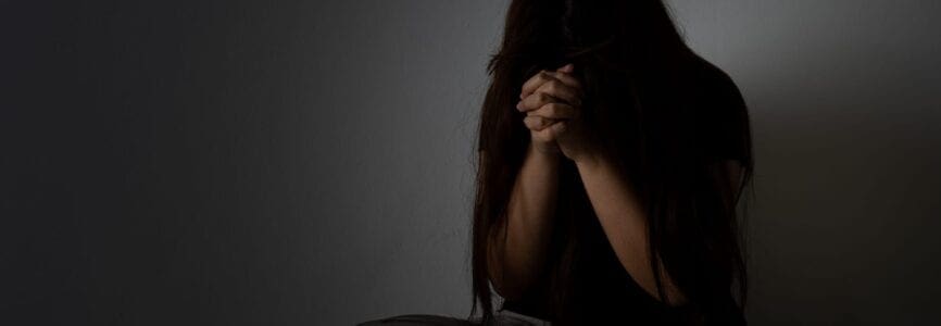 sad woman hug her knee and cry sitting alone in a dark room. Depression, unhappy, stressed and anxiety disorder concept.