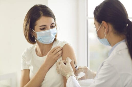 Young patient in a medical face mask getting an antiviral vaccine at the hospital